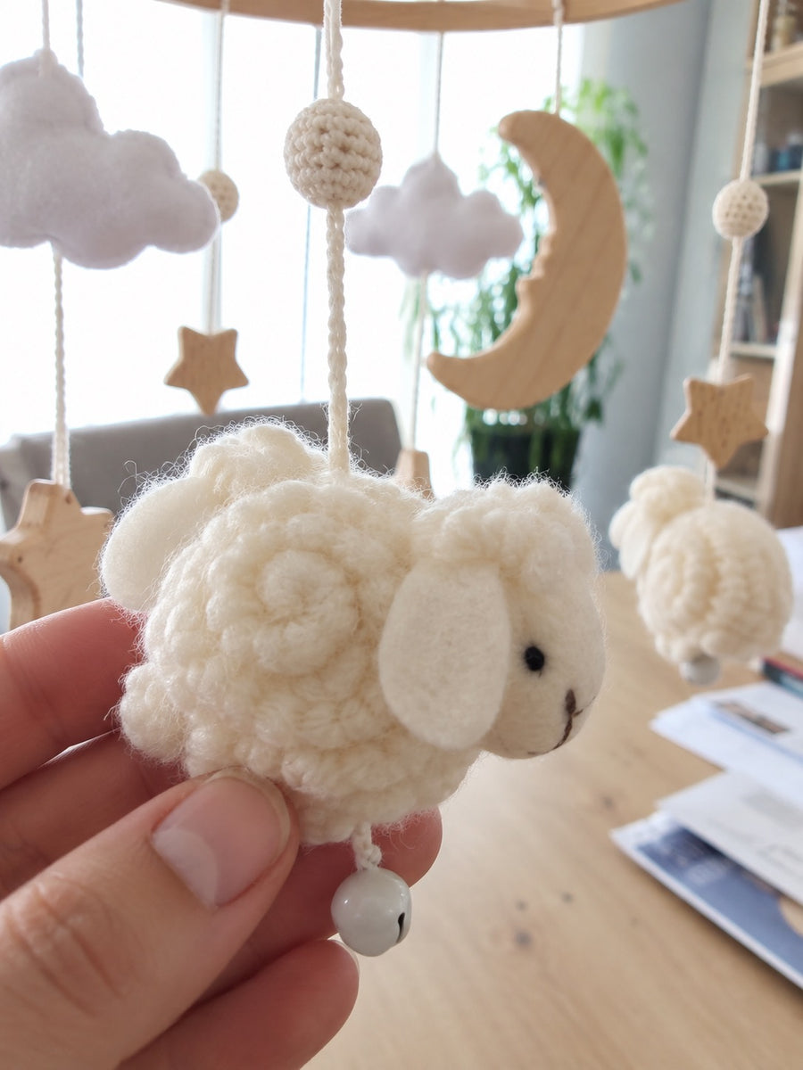 Close view of a soft White Sheep figure, cloud and wooden moon on a mobile